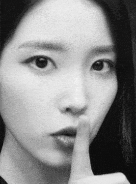 a close up of a woman 's face with her finger to her mouth