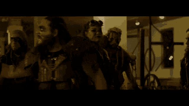 a group of people are standing in a dark room and one of them is holding a sword .