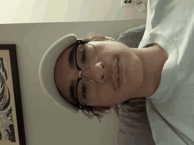 a man wearing glasses and a hat is laying on his back