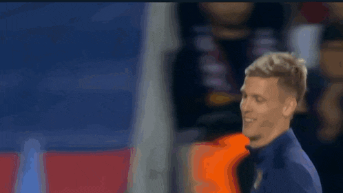 a soccer player wearing a blue shirt with a yellow sticker on it is smiling .