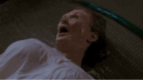 a woman is laying on the floor with her mouth open and a hose coming out of her mouth .