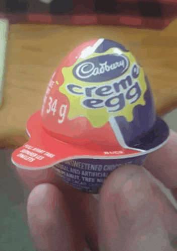 a cadbury creme egg is being held in someone 's hand