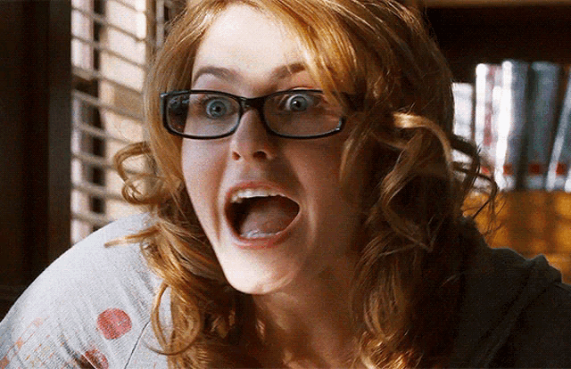 a woman wearing glasses looks surprised with her mouth wide open