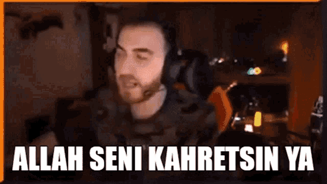 a man wearing headphones is sitting in front of a microphone and saying allah seni kahretsin ya .