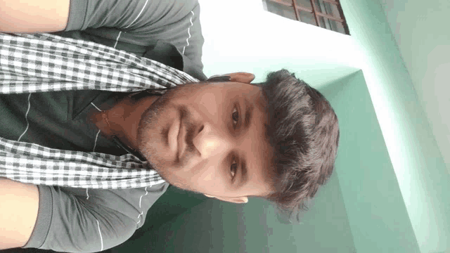 a man wearing a scarf around his neck looks down at the camera