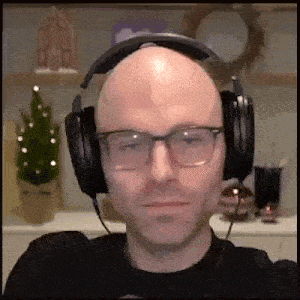 a bald man wearing glasses and headphones looks at the camera .