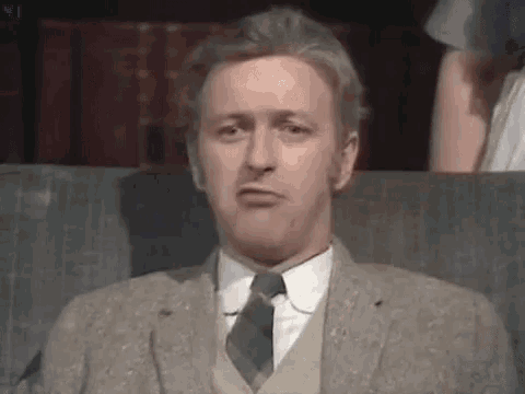 a man in a suit and tie is sitting on a couch .
