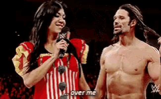 a woman is talking into a microphone next to a shirtless man who says over me