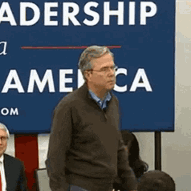 a man stands in front of a sign that says ' leadership america '