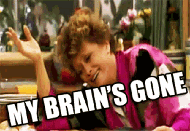 a woman in a pink jacket is laying at a table with the words " my brain 's gone " above her