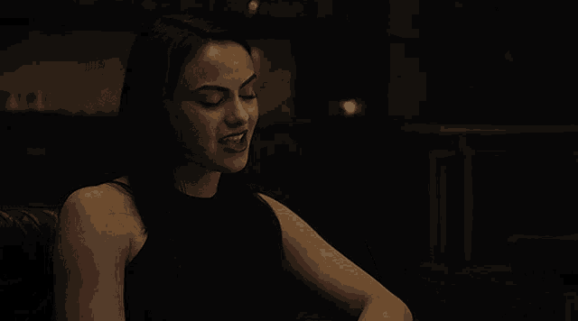 a woman in a black dress is sitting on a couch with her eyes closed