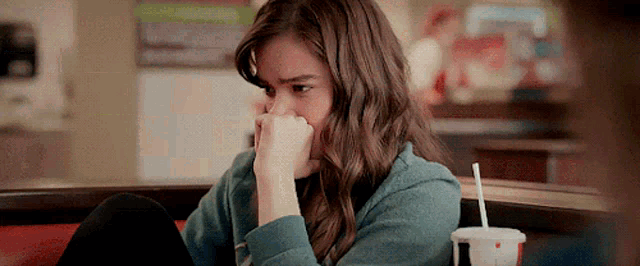 a young woman is sitting at a table with her hand on her face .