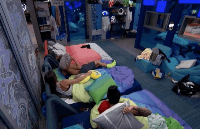 a group of people laying on a bed with pillows in a room