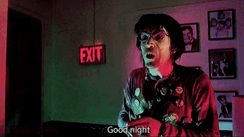 a man in a red jacket is standing in front of an exit sign .
