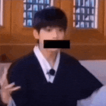 a man with a black tape over his mouth is making a funny face .