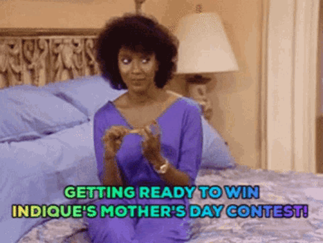 a woman is sitting on a bed with the words getting ready to win indicue 's mother 's day contest above her