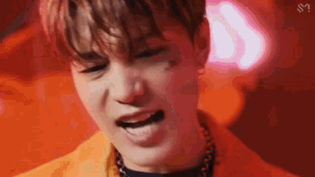 a close up of a young man 's face with his mouth open and a red background .