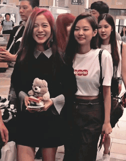 a woman wearing a supreme shirt is holding a stuffed animal