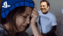 a woman wearing a blue hat with the playstation logo on it is crying in front of a man .