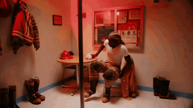 a man in a fireman 's uniform sits in a room