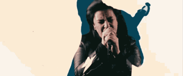 a woman singing into a microphone with a shadow of a person behind her