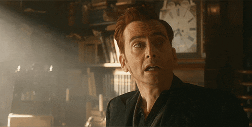 a man with red hair is standing in front of a clock with the hands on the number 12
