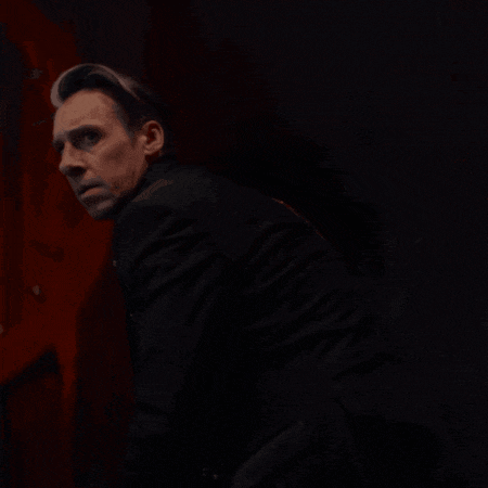a man in a suit stands in front of a red door
