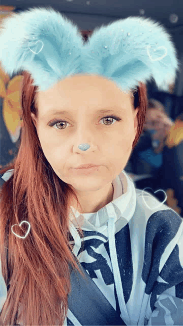 a woman wearing a blue bunny ear headband with hearts on them