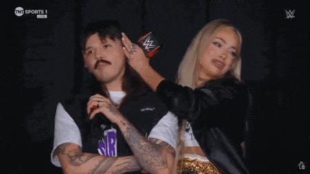 a man and a woman are standing next to each other and the woman is touching the man 's hair .