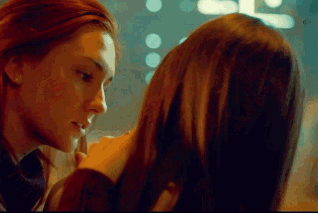 a woman with red hair is touching another woman 's forehead