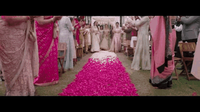 a bride and groom are walking down the aisle at a wedding surrounded by flowers .