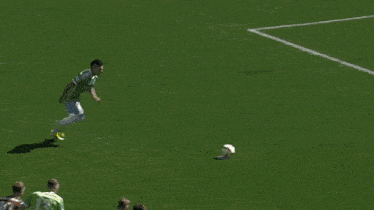 a man in a green shirt is running towards a goalie