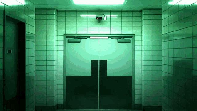 a hallway with green tiles and a door with a cross on it
