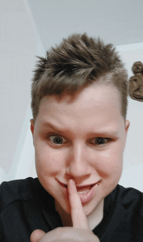 a young man holds his finger to his mouth in a gesture of silence
