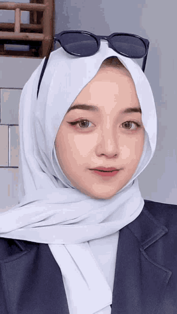 a woman wearing a hijab and sunglasses is looking at the camera