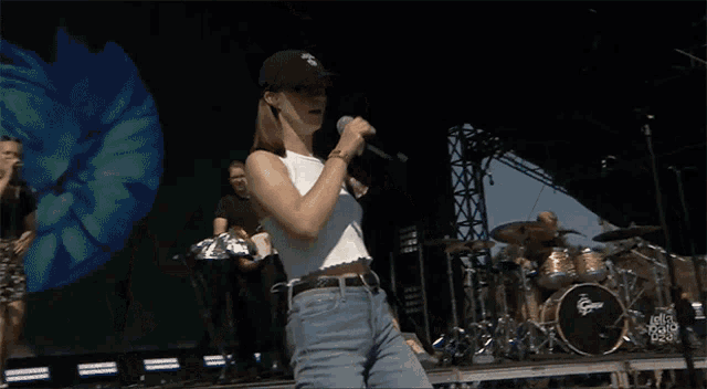 a woman singing into a microphone in front of a drum set that says gretsch on it