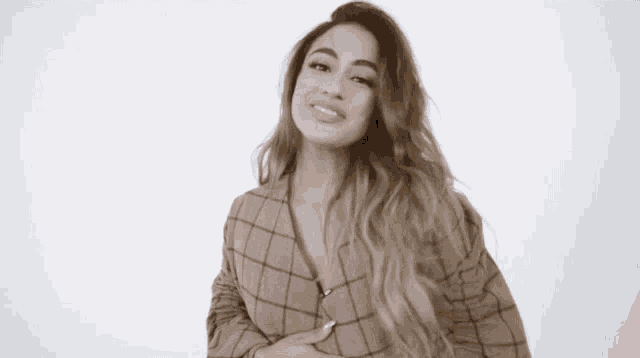 a woman is wearing a plaid jacket and smiling .