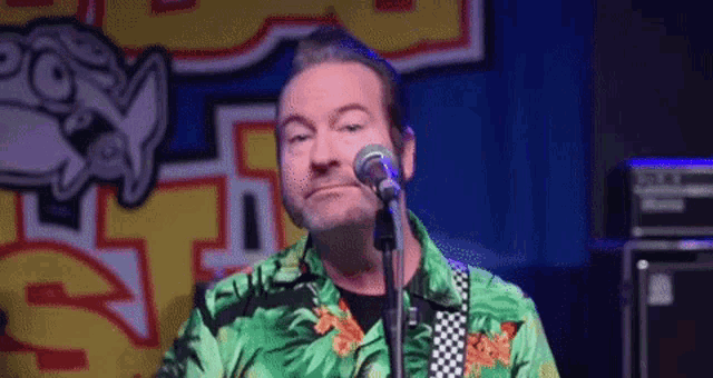 a man is standing in front of a microphone wearing a green shirt .