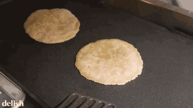 two tortillas are being cooked on a griddle with the word delish in the upper right corner