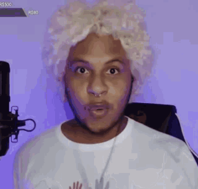 a man wearing a white wig and headphones is standing in front of a microphone .