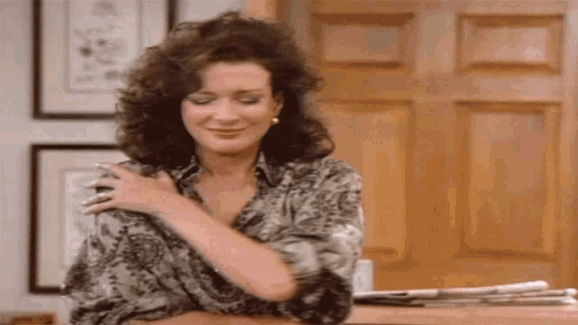 a woman with curly hair is hugging herself