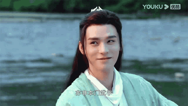 a man with long hair and a crown on his head is smiling in front of a river .