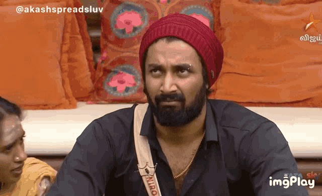 a man with a beard wearing a red beanie and a strap that says niro