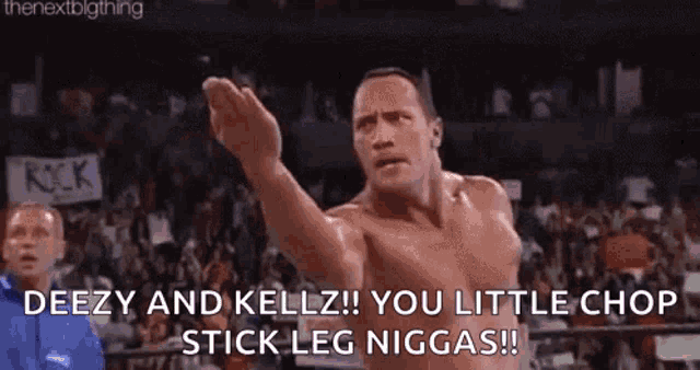 a shirtless wrestler is standing in a wrestling ring with his fist in the air and a crowd behind him .