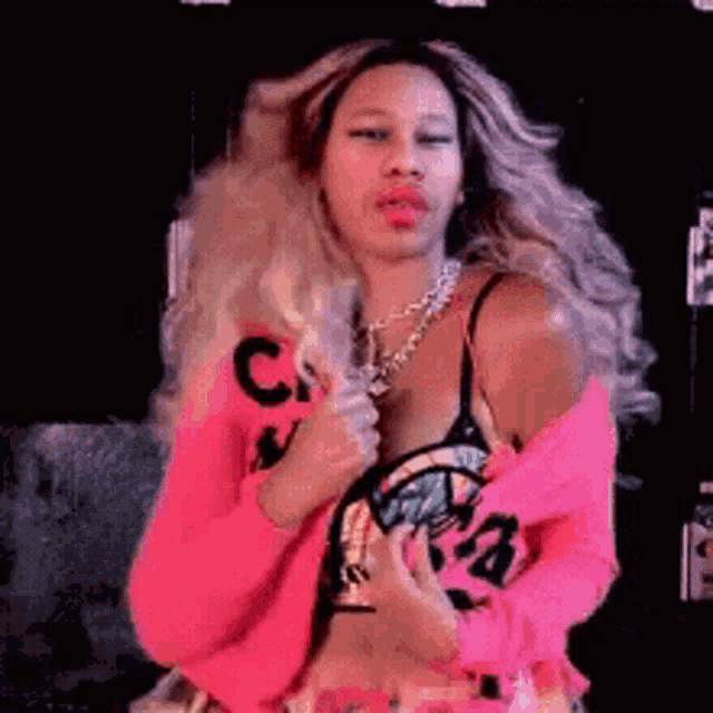 a woman is wearing a pink sweater with the letter c on it