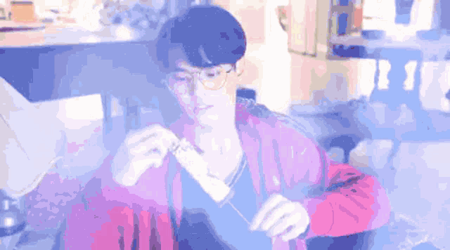 a man wearing glasses and a pink jacket is holding something
