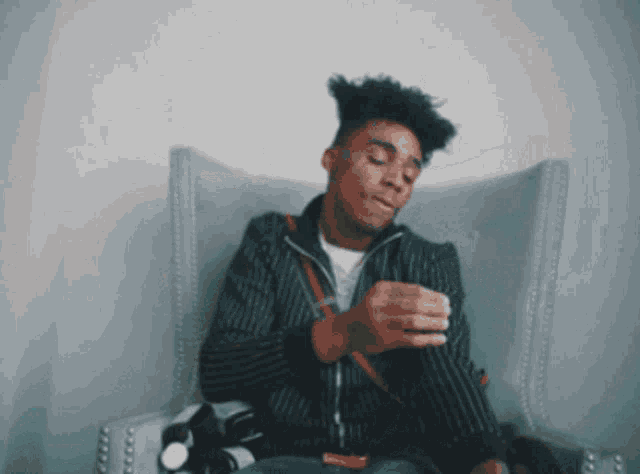 a man in a striped jacket is sitting in a chair with his eyes closed