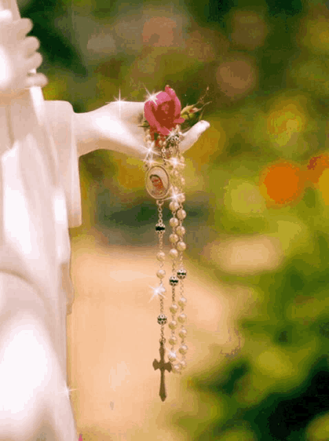 a statue of a woman holding a rosary with a rose in her hand
