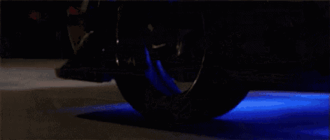a car is driving down a road at night with blue lights on the tires .