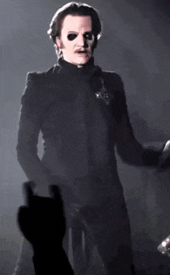 a man in a black suit is standing on a stage in front of a microphone .